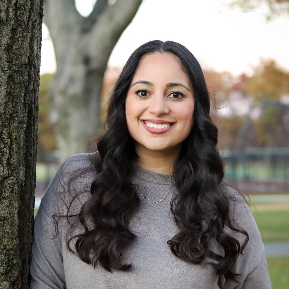 A woman with long dark hair is smiling for the camera.