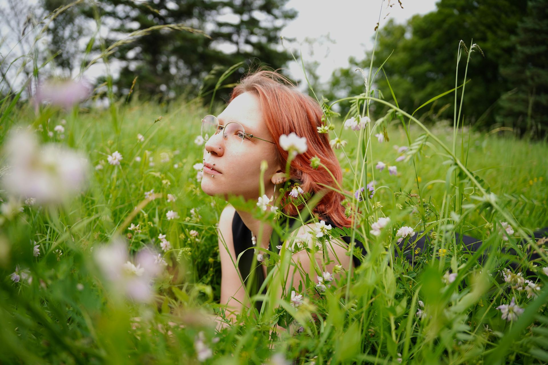 A woman is laying in a field of tall grass and flowers.