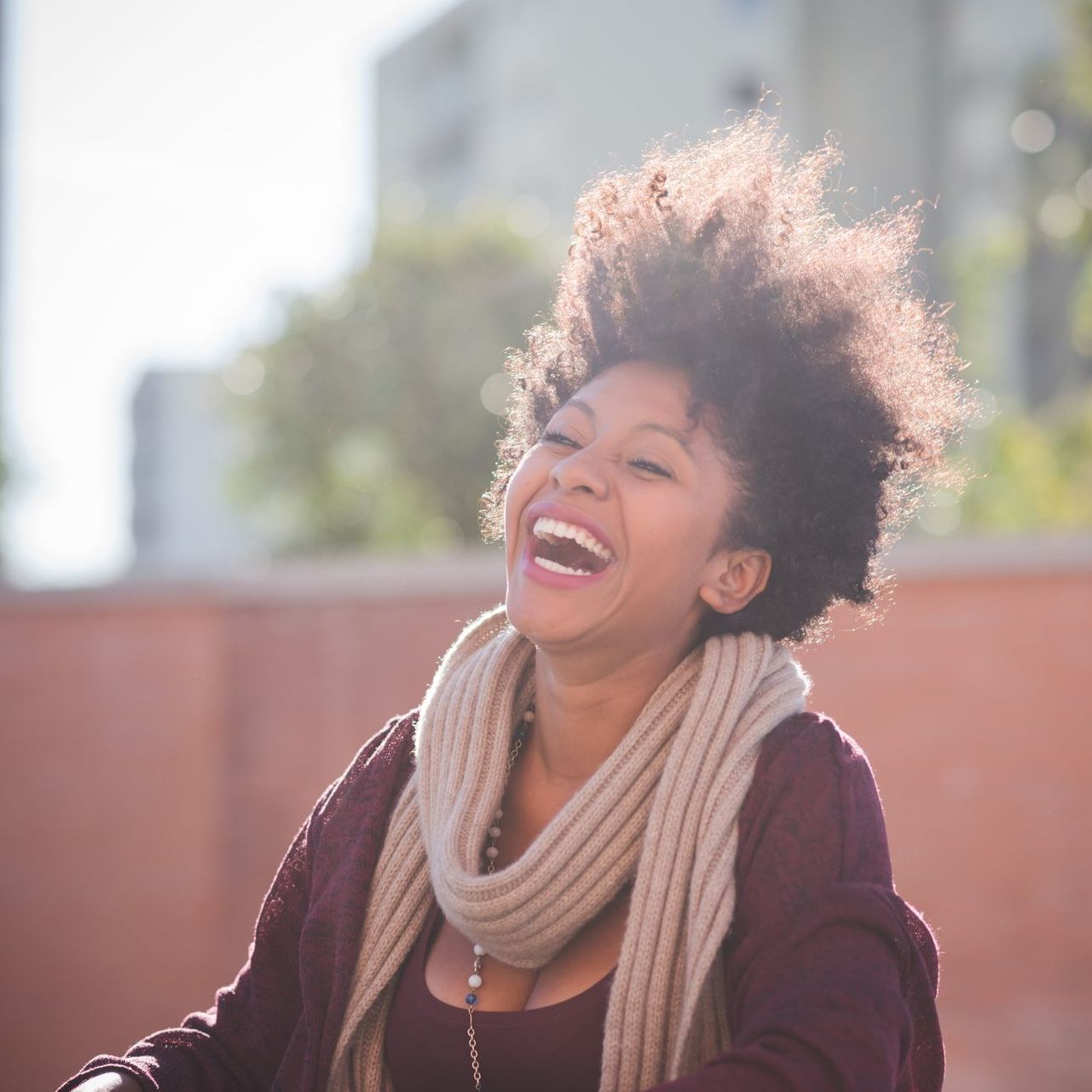 A woman wearing a scarf and a sweater is laughing