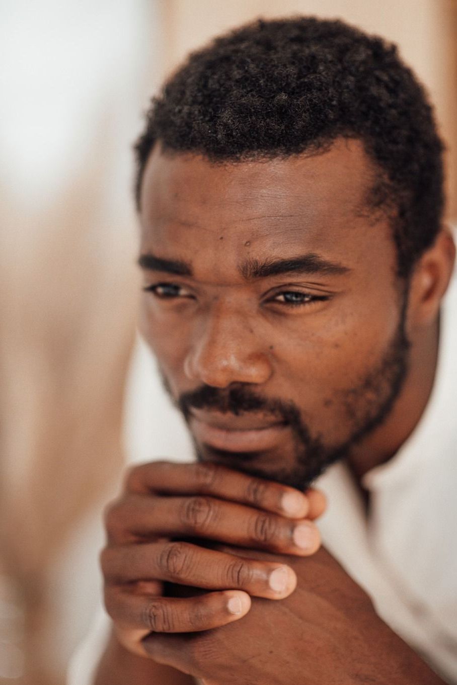 A woman is sitting in a chair with her hands on her chin.