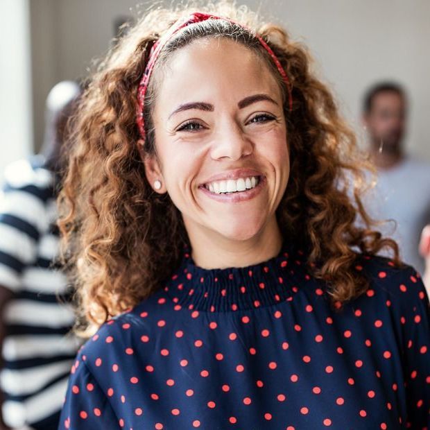 A young woman is leaning against a brick wall in a hallway.