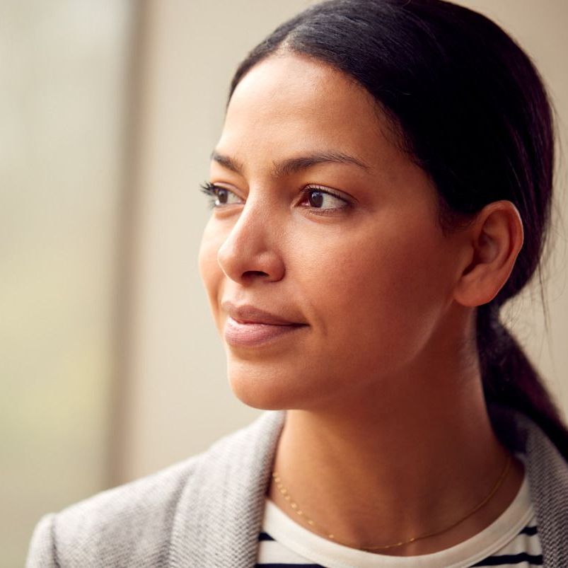 A woman is sitting in a chair with her hands on her chin.