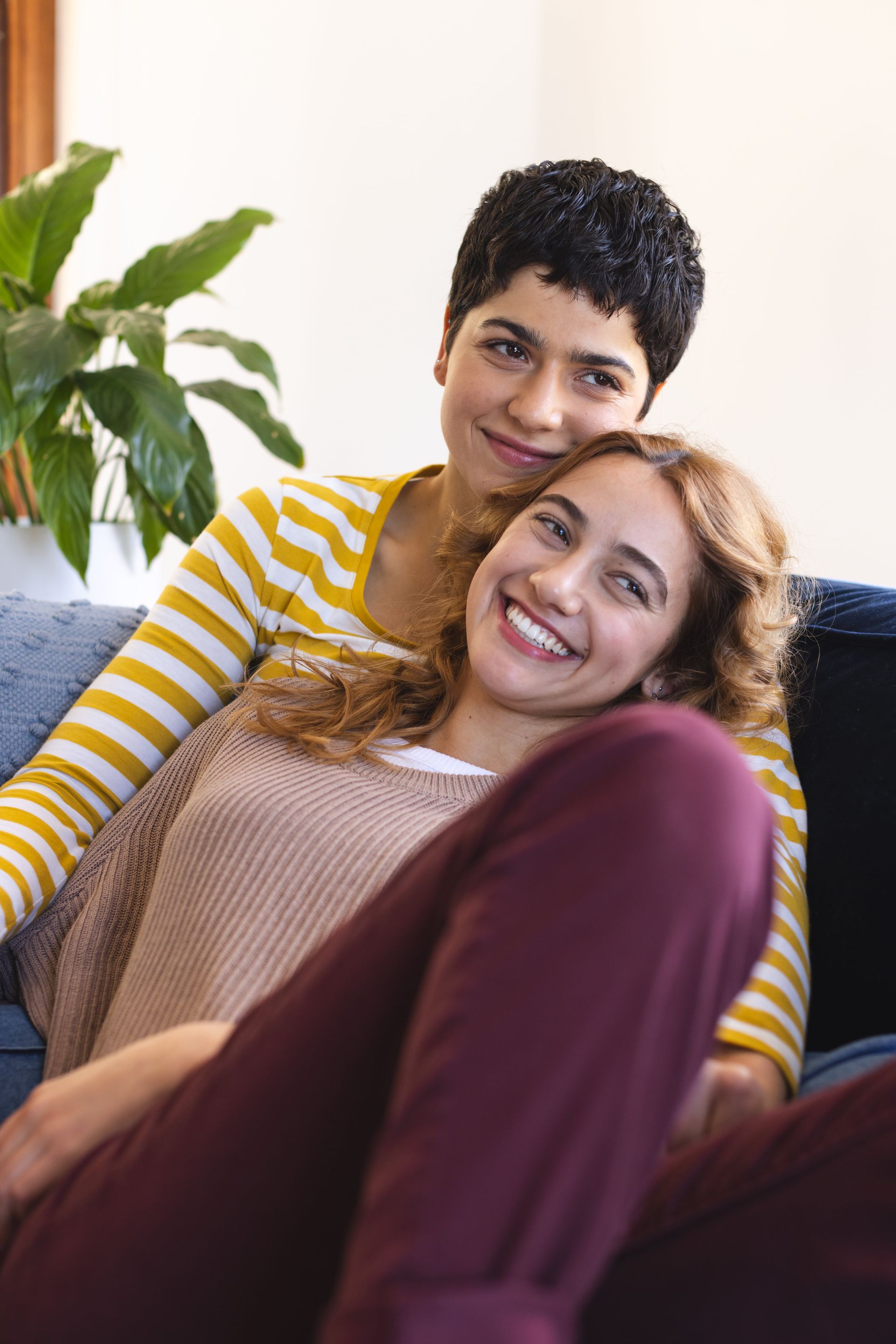 Two women are sitting on a couch together and smiling.