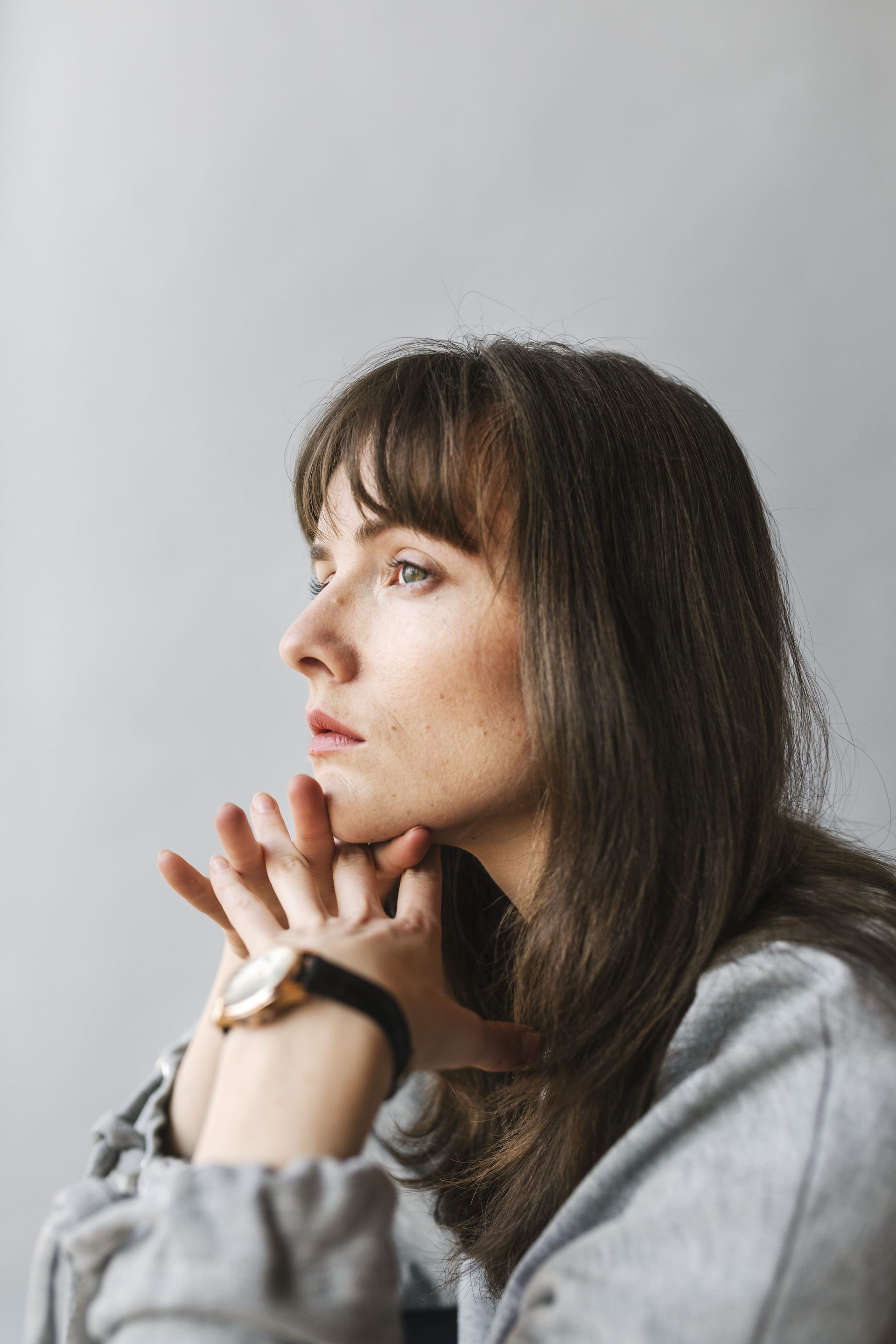A woman wearing a watch is looking out of a window.