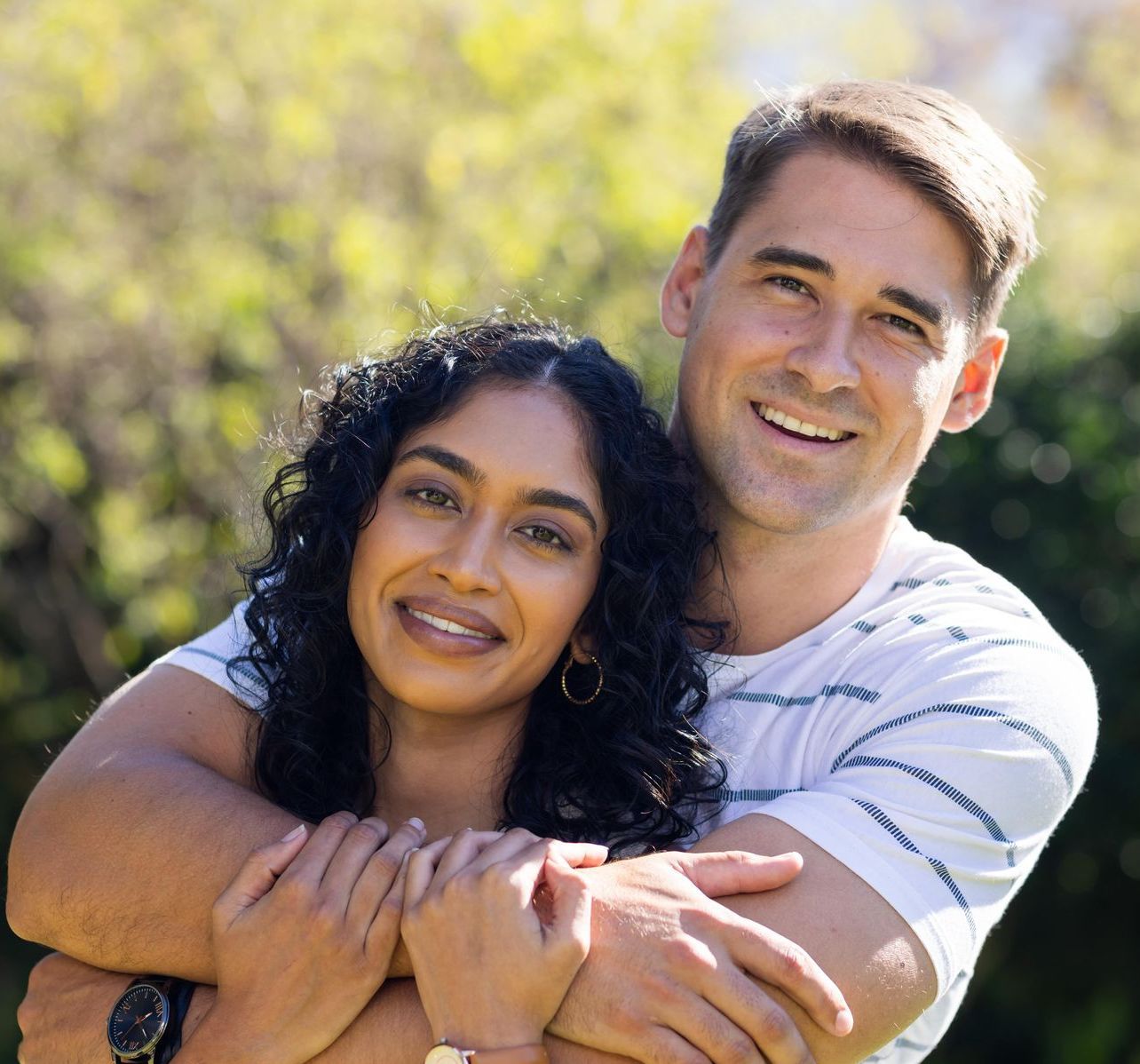 A man and woman are hugging each other and smiling for the camera.