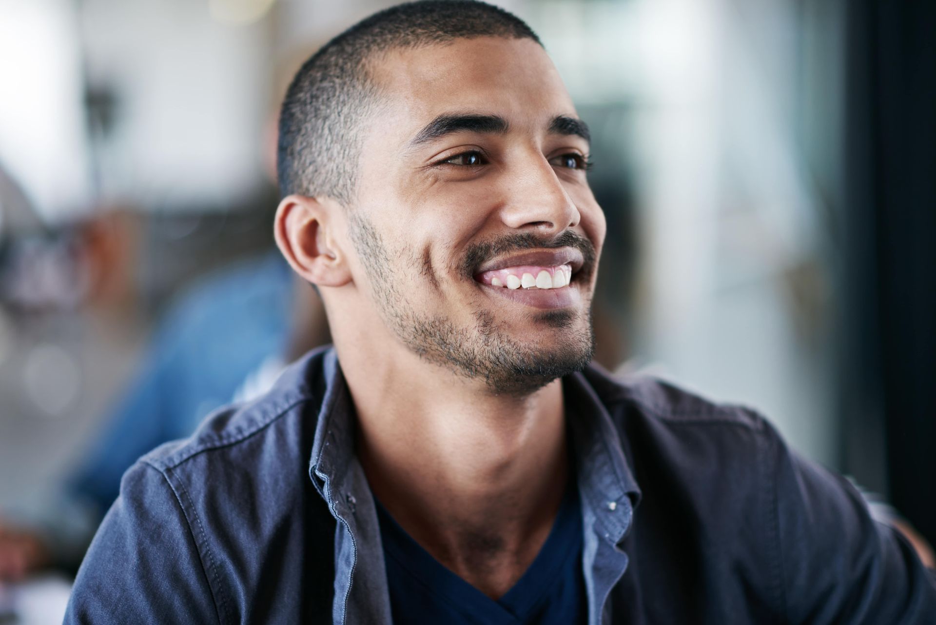 A man with a beard is smiling while sitting at a table.