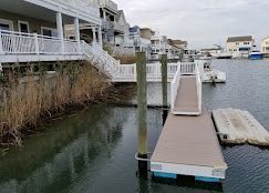 A dock in the middle of a body of water next to a house.