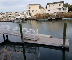 A dock in the middle of a body of water with houses in the background.