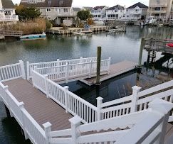 A dock with a white railing and stairs overlooking a body of water.