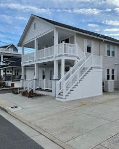 A large white house with stairs leading up to the second floor.