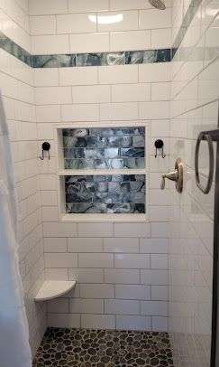 A shower with white tiles , a seat , and a window.