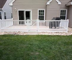 A white deck with a white railing is in front of a house.
