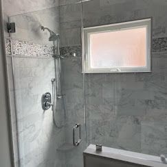A bathroom with a walk in shower and a window.