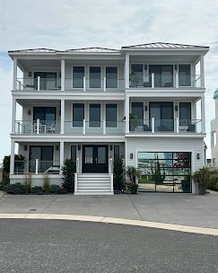 A large white house with a lot of windows and balconies is sitting on top of a hill.