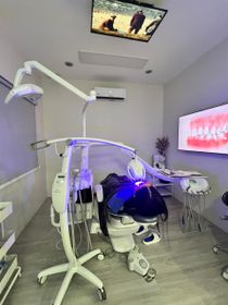 Dentist's office with dental chair, tools, and TV showing teeth.
