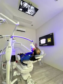 A person in a dental chair receives teeth whitening treatment in a modern clinic.