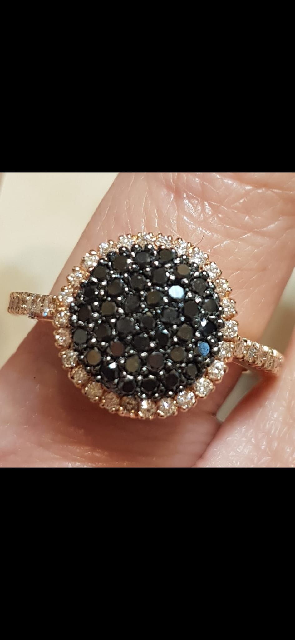Anello in oro rosa con pietra preziosa nera centrale circondata da piccoli diamanti.