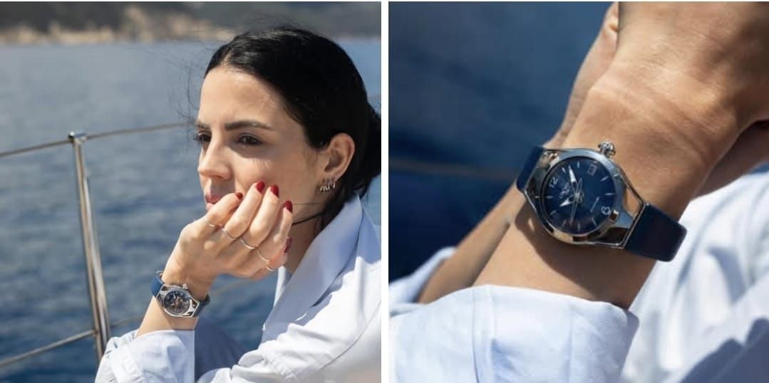 Donna su una barca, con un orologio in mano. Ha i capelli scuri e guarda altrove, con una mano vicino al viso.