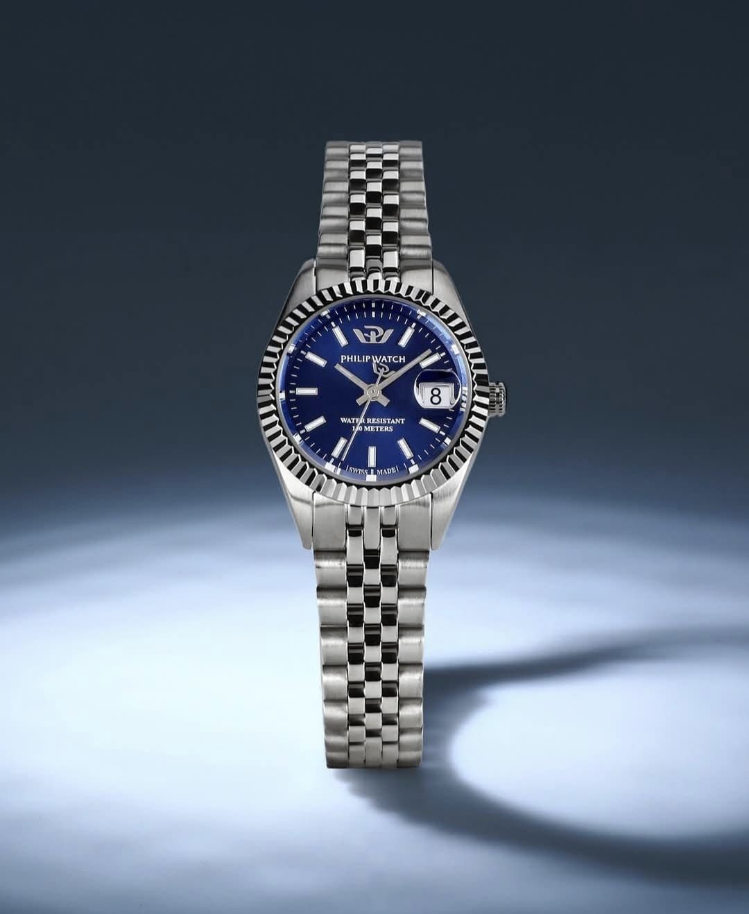 Orologio da polso in argento con quadrante blu, cinturino in metallo e lunetta scanalata.