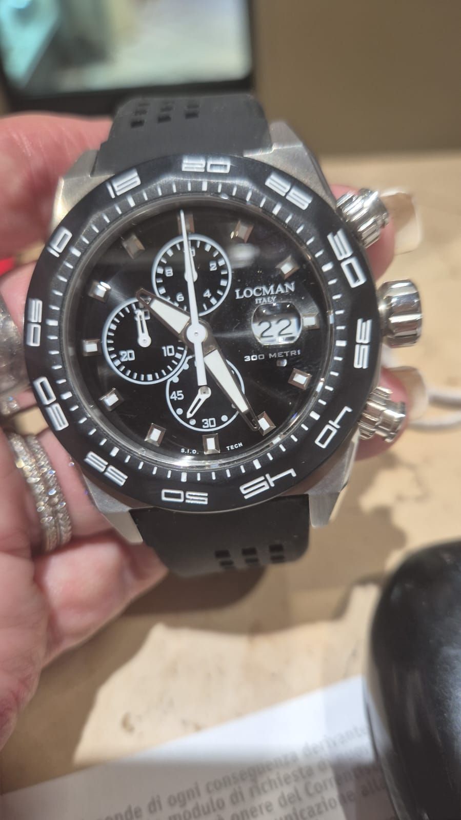 Orologio da polso nero e argento con quadrante nero e cinturino in gomma, da tenere in mano.