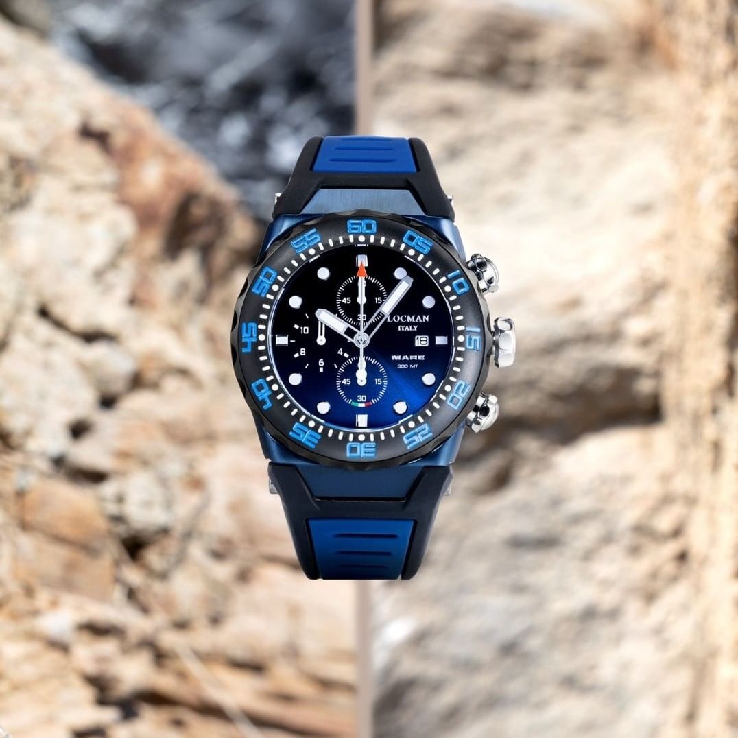 Orologio da polso blu e nero su uno sfondo sfocato di rocce e pilastri.