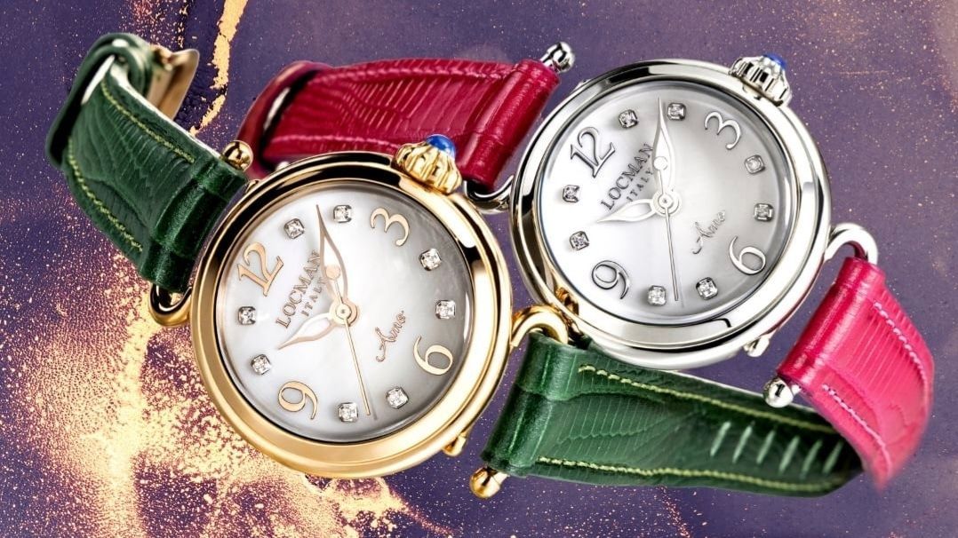 Due orologi con quadranti bianchi, dettagli di diamanti e figure di ballerine; uno in oro e uno in argento, con cinturini verdi e rossi.