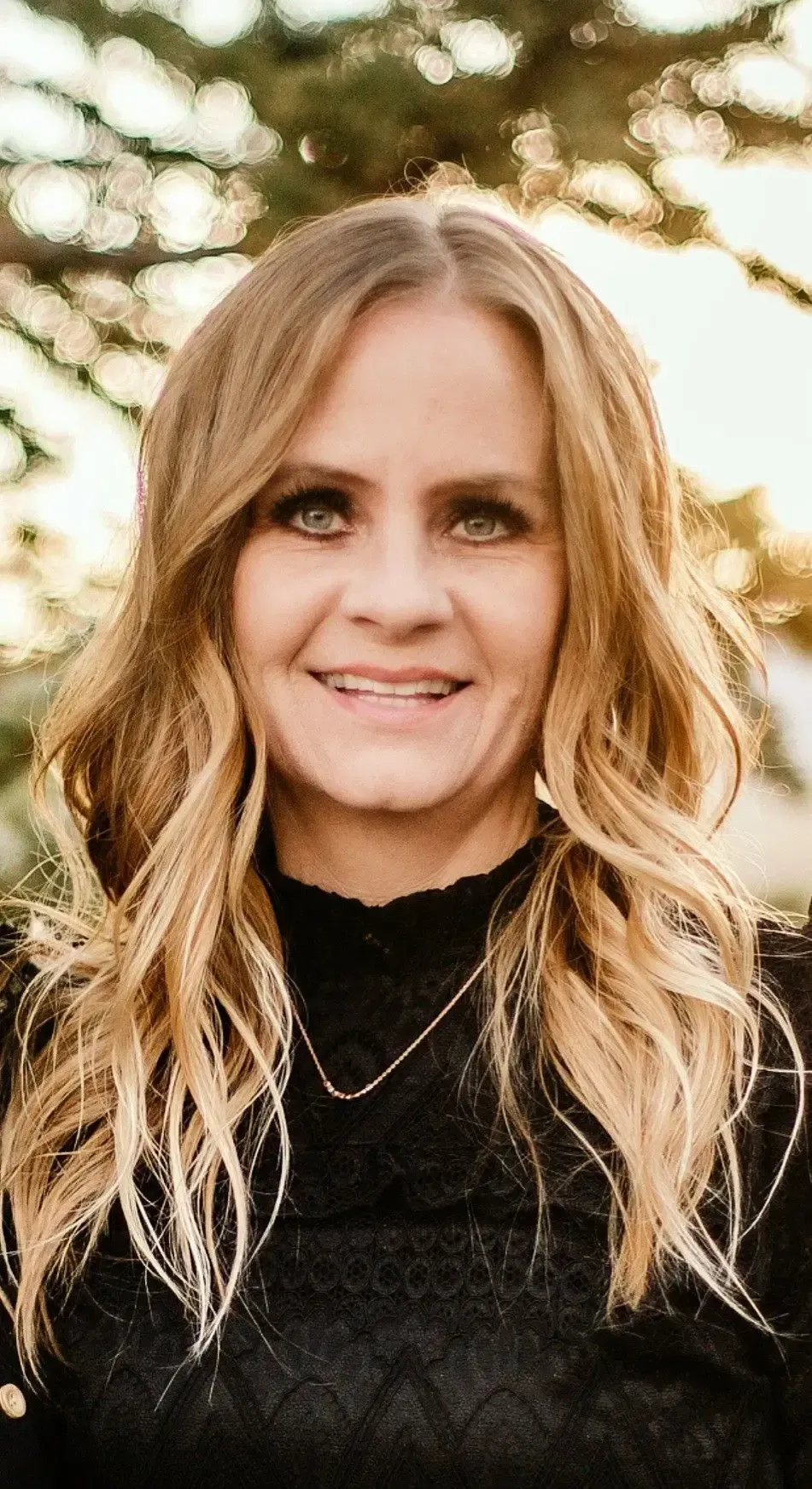 a woman with long blonde hair is smiling for the camera