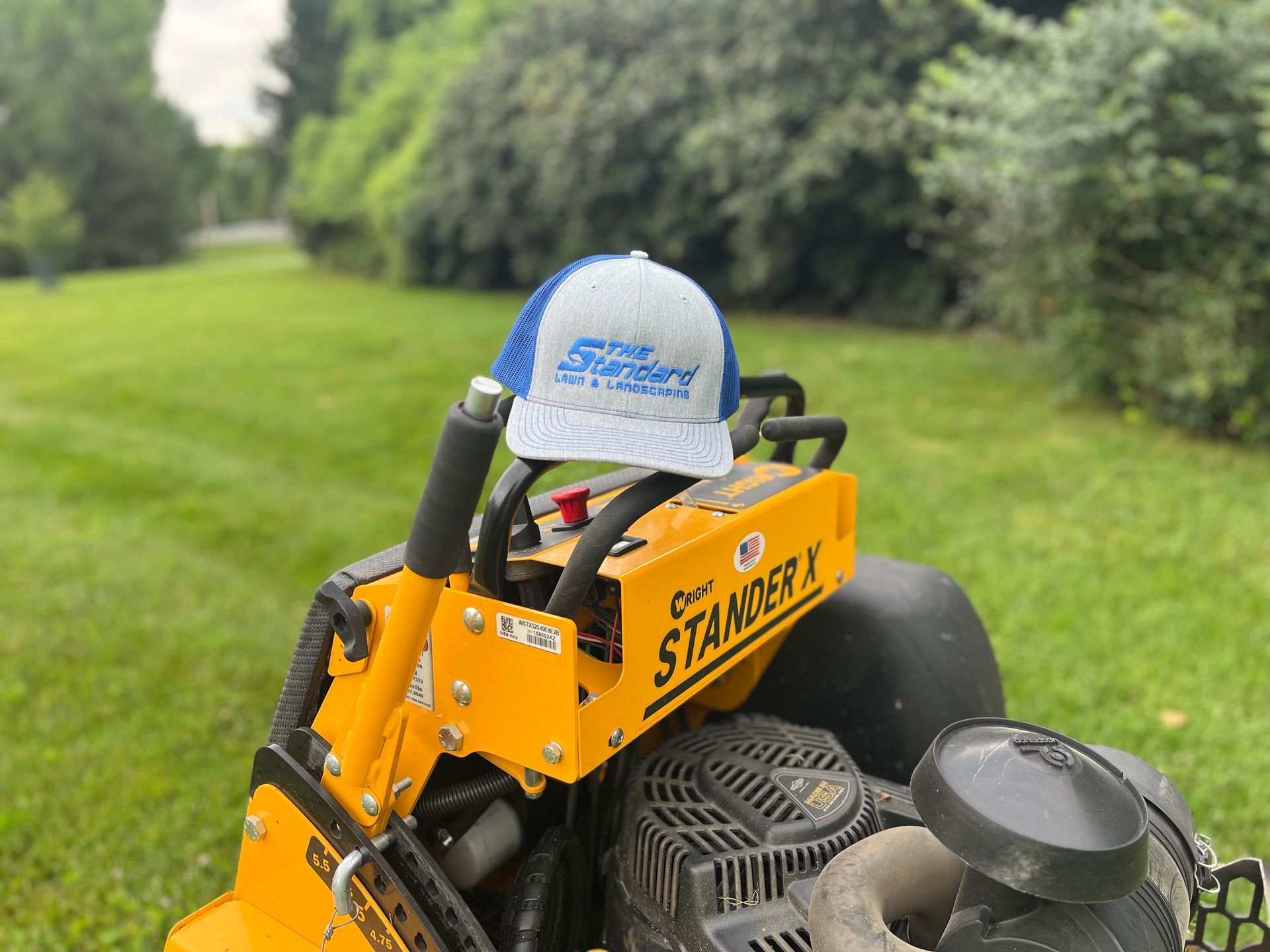A hat is sitting on the back of a lawn mower.