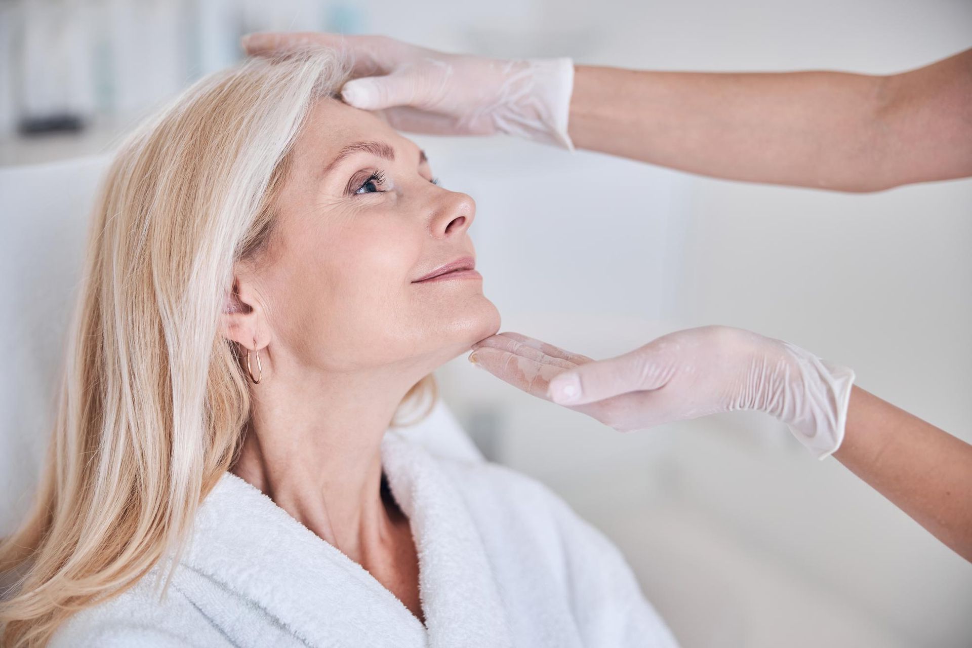 A woman is getting her face examined by a doctor.