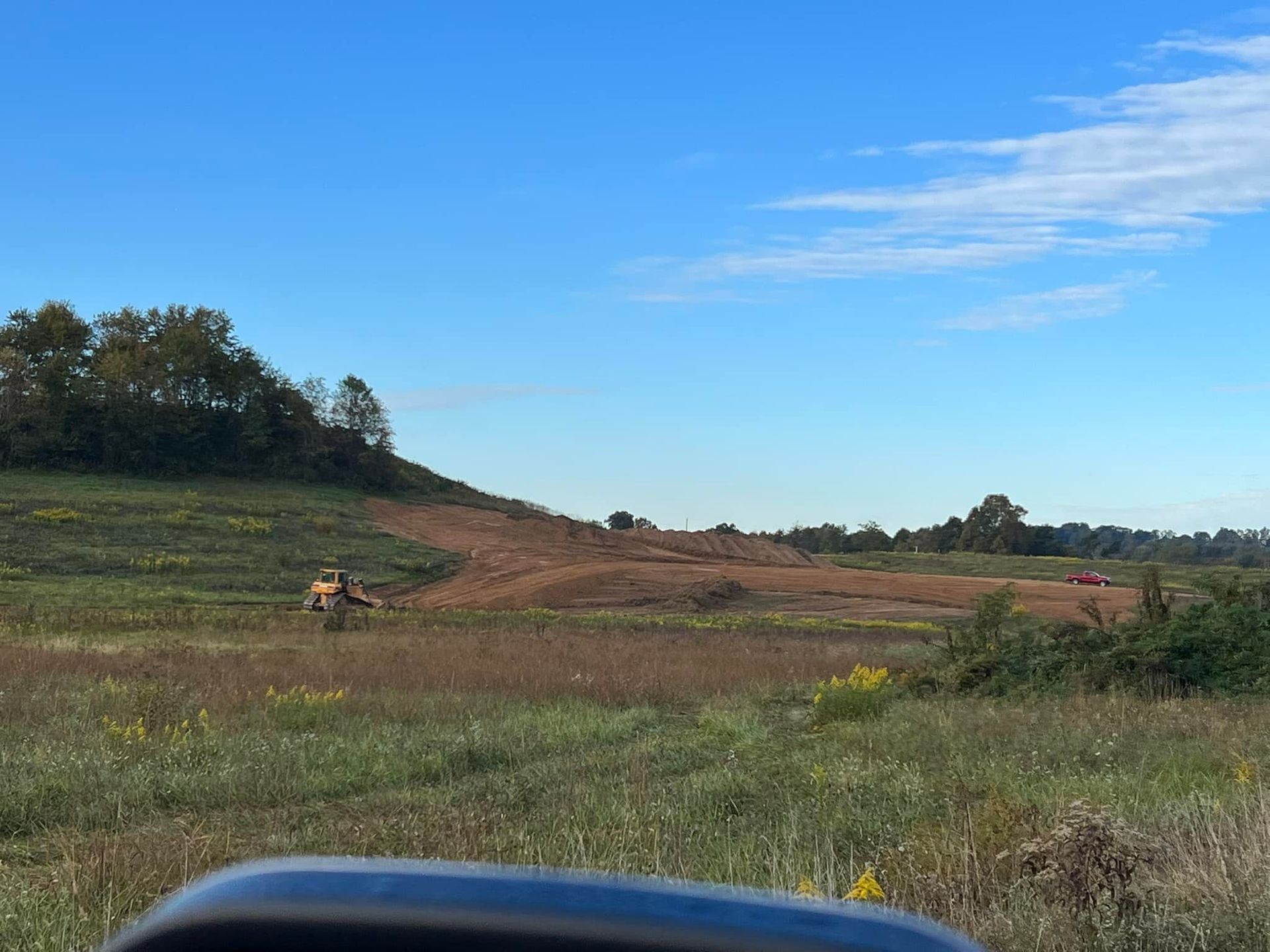 A truck is driving down a dirt road in a field