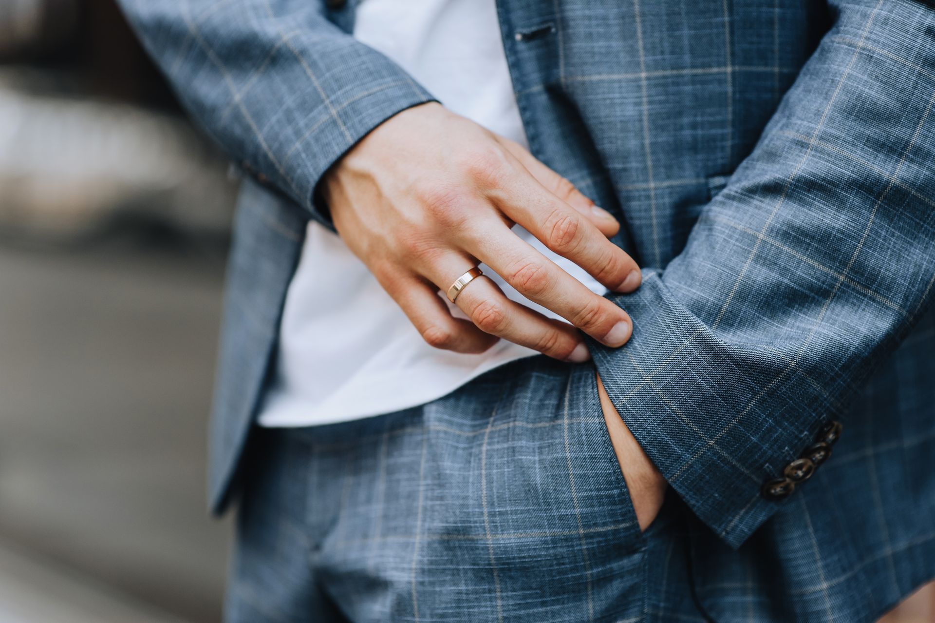 Man in blue plaid suit, hand in pocket, showing ring.