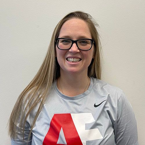 A woman wearing glasses and a nike shirt is smiling for the camera.