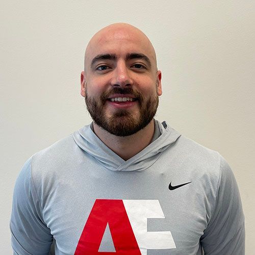 A bald man with a beard is wearing a grey nike hoodie.
