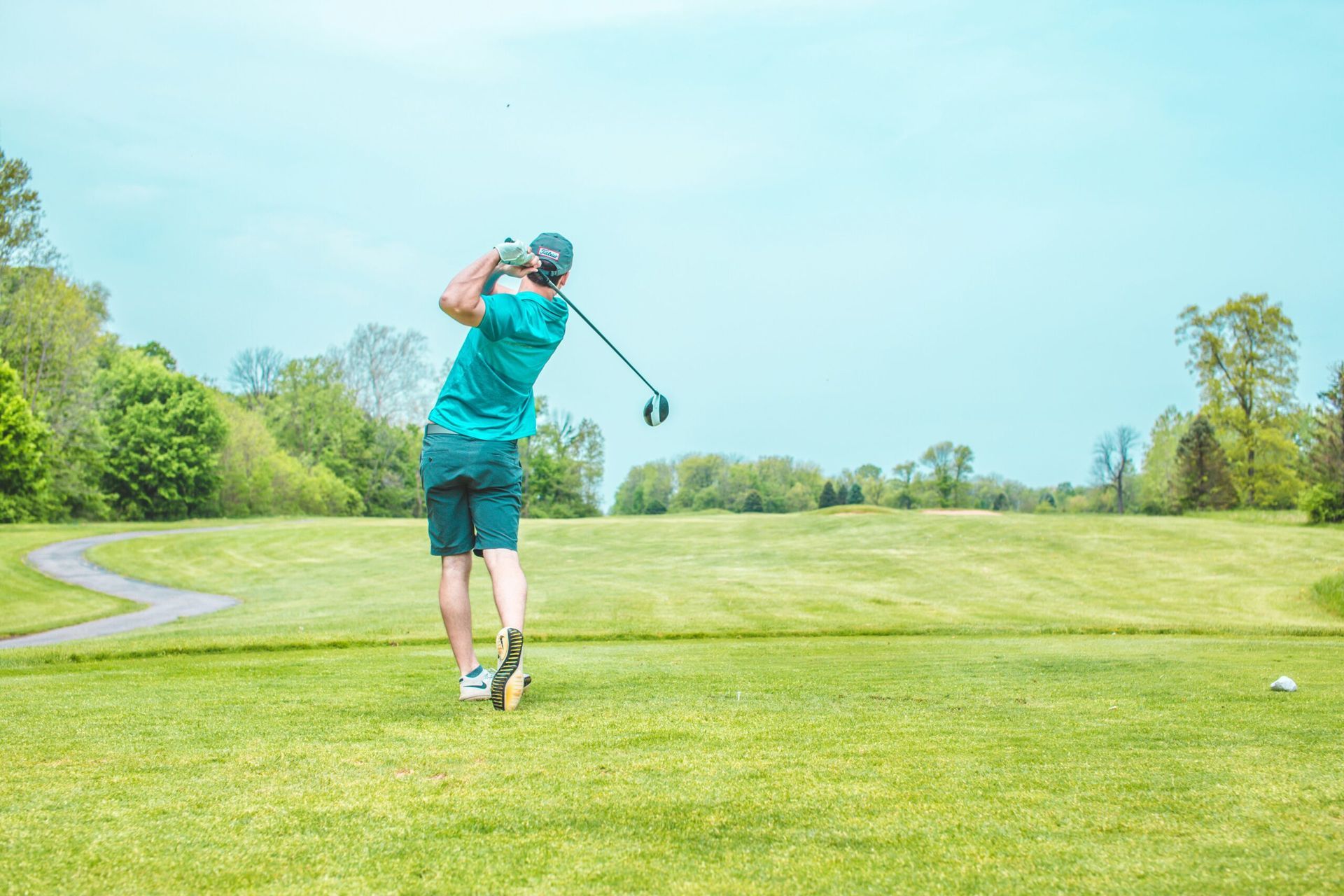 A man is swinging a golf club on a golf course.