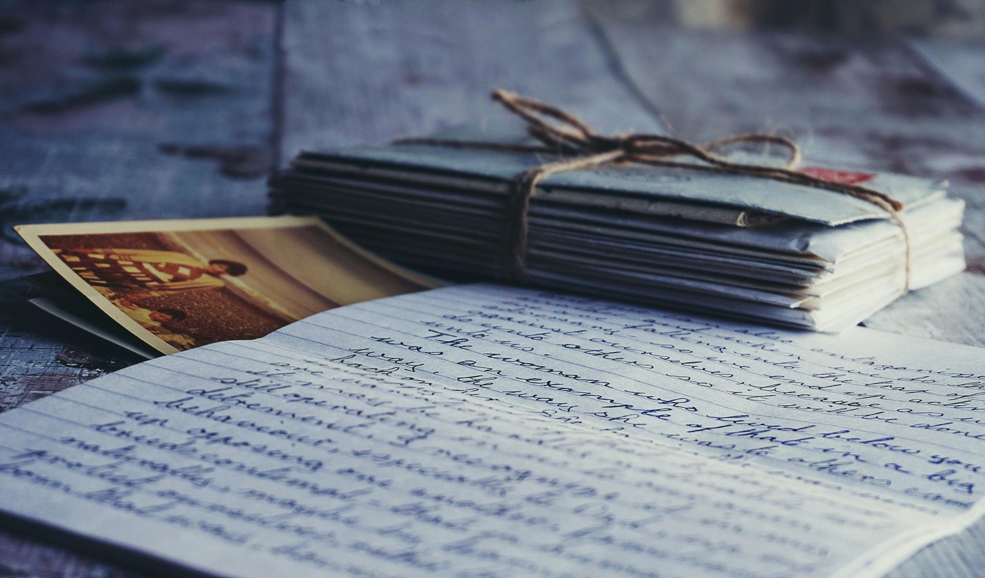 A stack of letters is tied with string on top of a piece of paper.