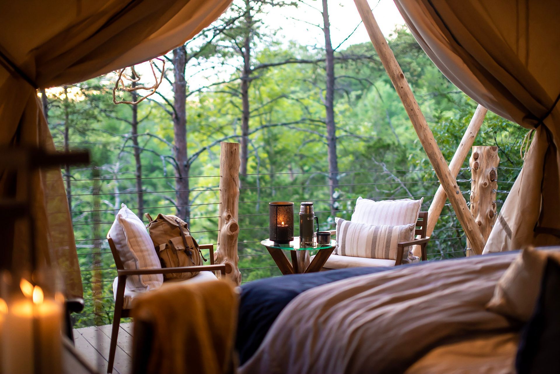 A bedroom in a tent with a view of the woods.