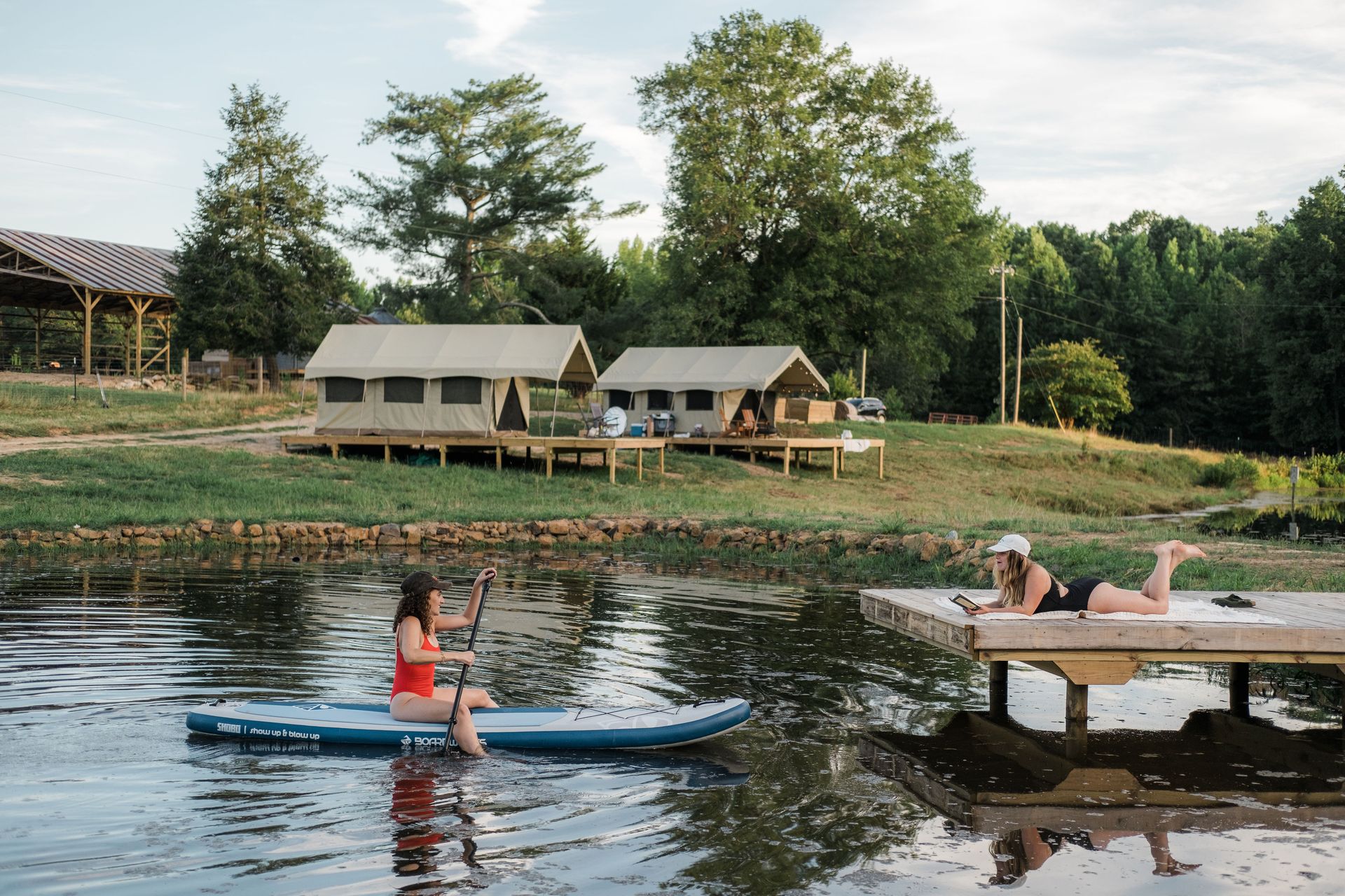 Two women are sitting on paddle boards in the water.