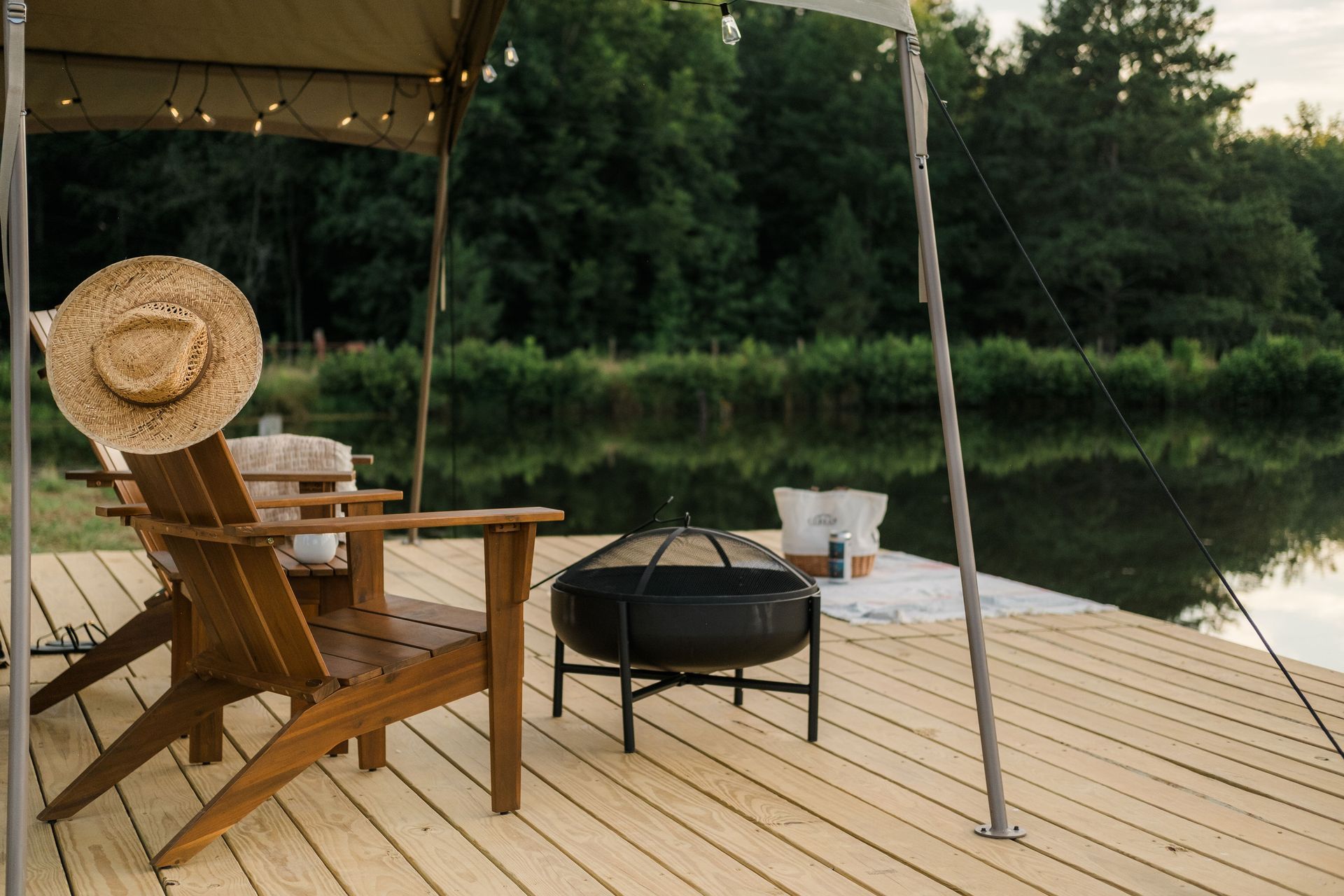 A dock with two chairs and a fire pit next to a lake.
