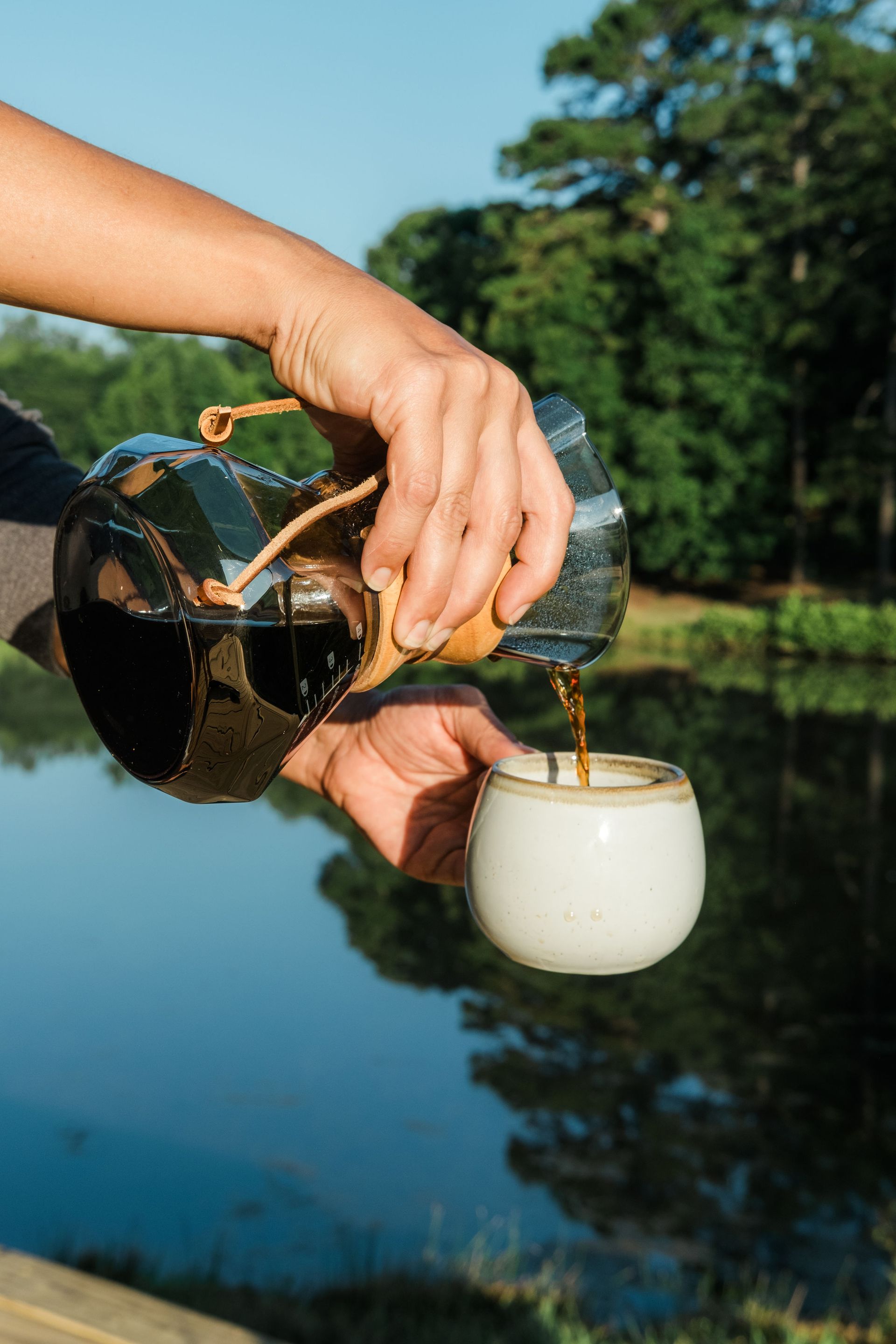 A person is pouring coffee from a coffee pot into a cup.