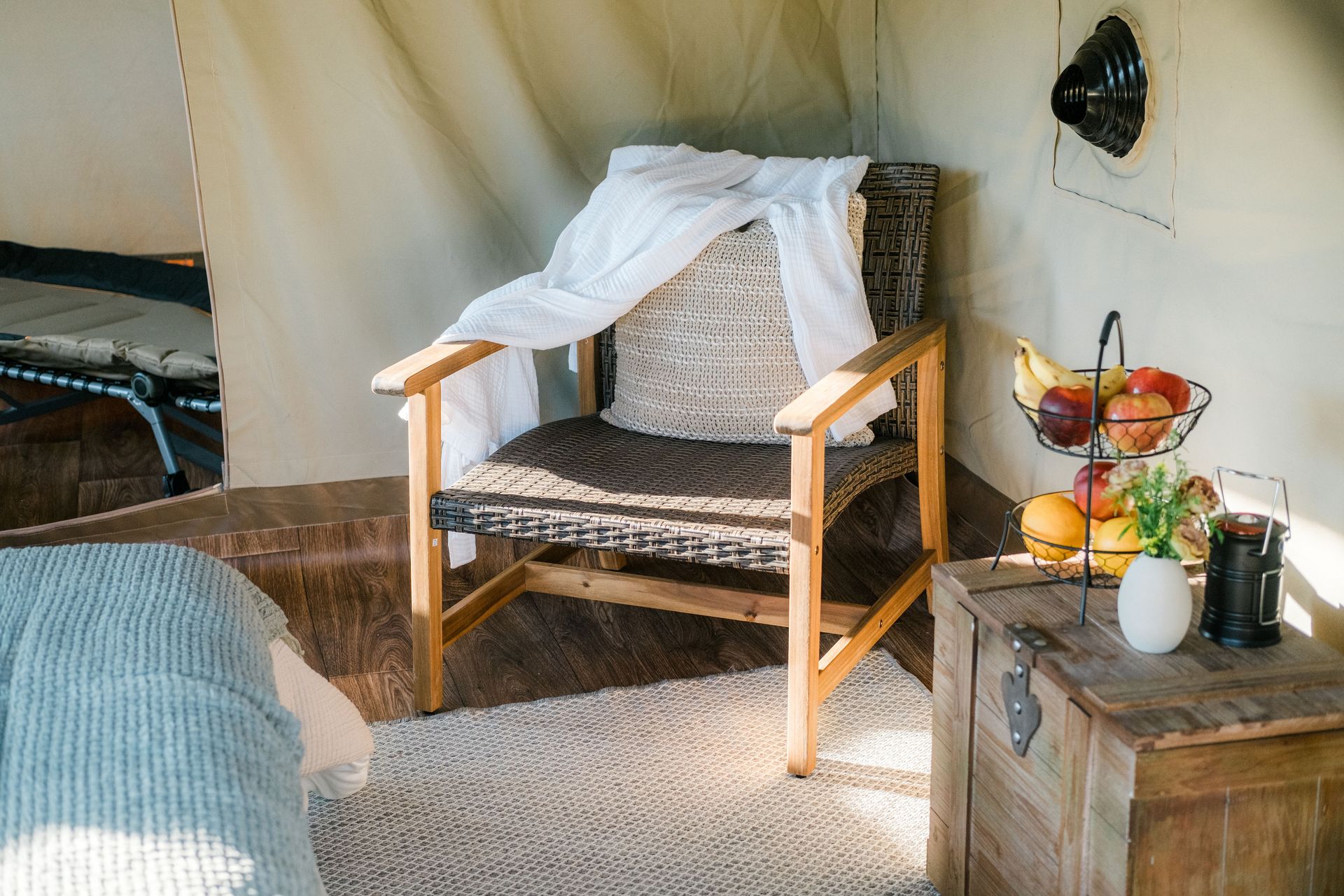 A chair is sitting in a tent next to a basket of fruit.