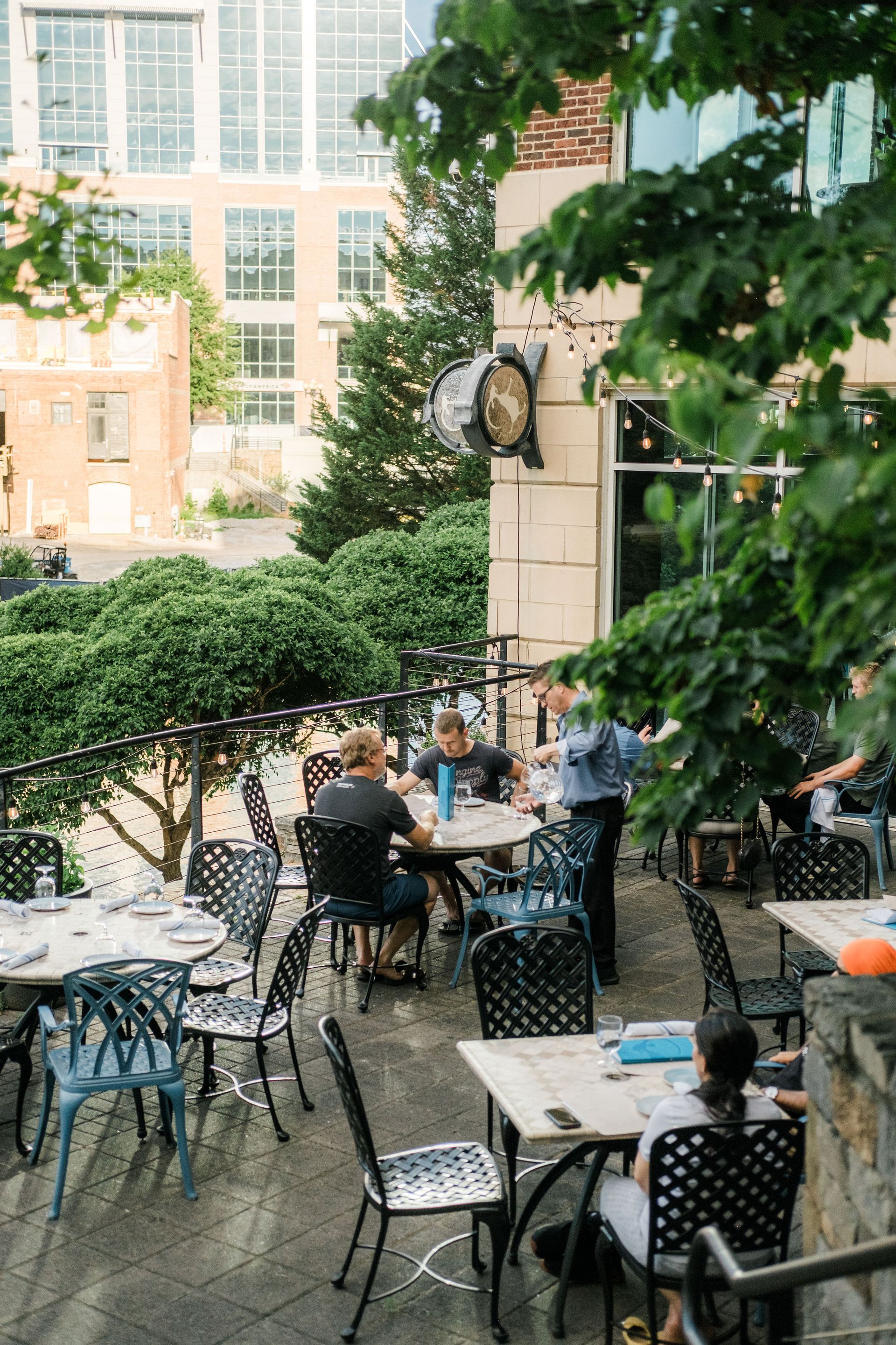 A group of people are sitting at tables outside of a restaurant.