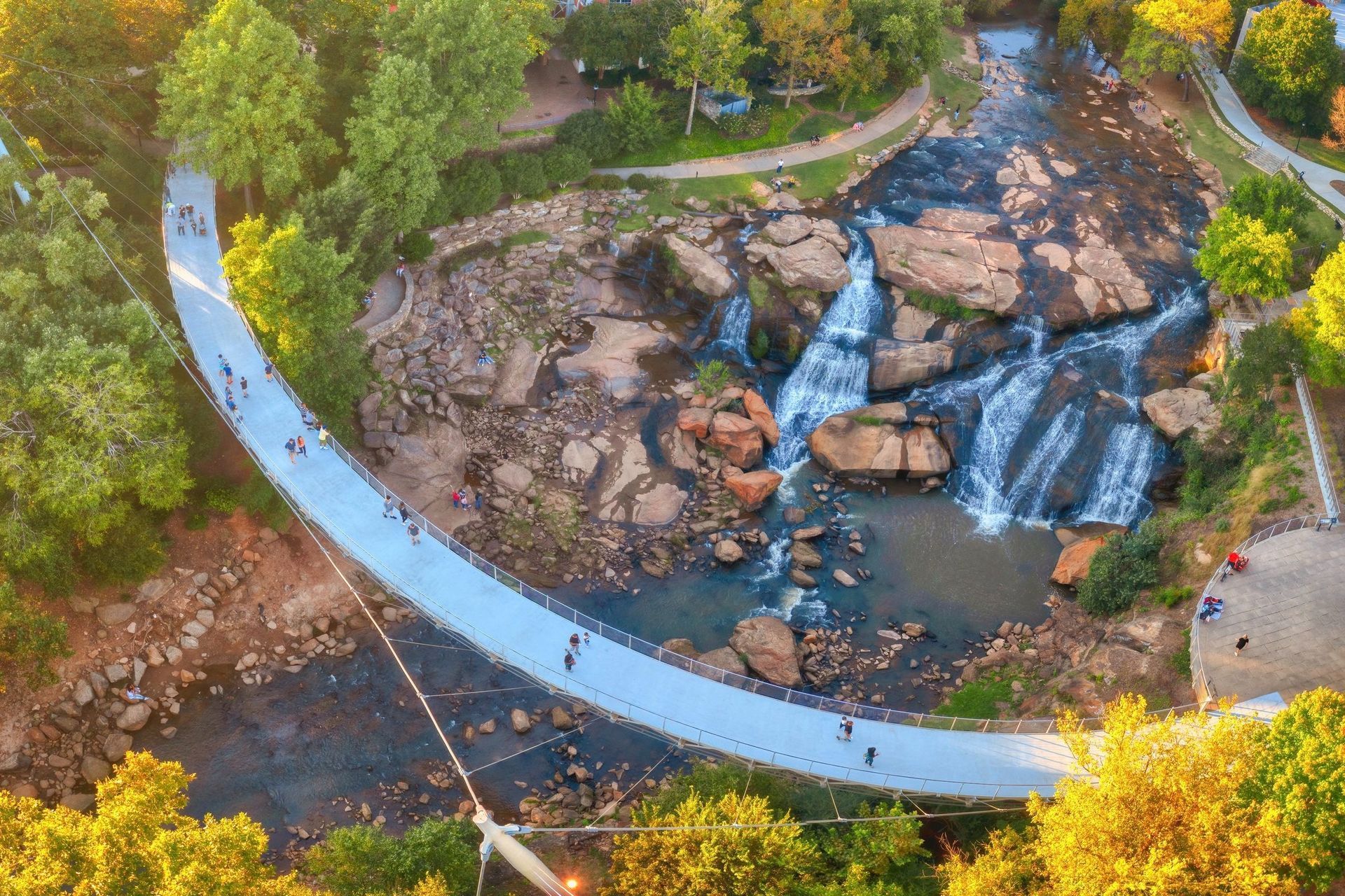 An aerial view of a bridge over a river with a waterfall in the background.
