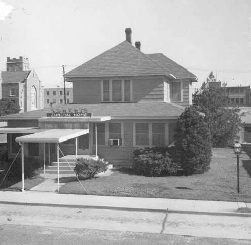 Two-story building with a covered entrance, a sign that reads 