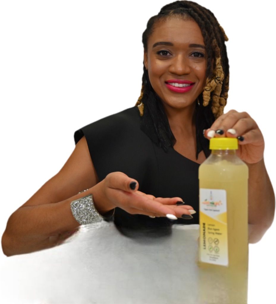 Woman holding a bottle of yellow liquid, smiling, and pointing. She wears a black top and bracelet.