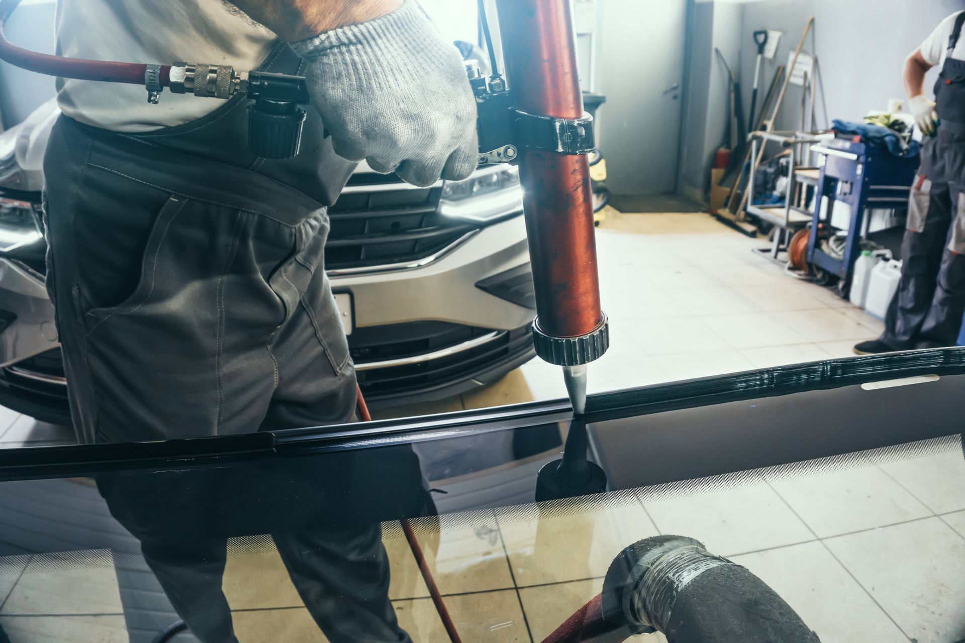 A man is installing a windshield on a car in a garage - Drummond, MT - Big Sky Auto Glass and Screens