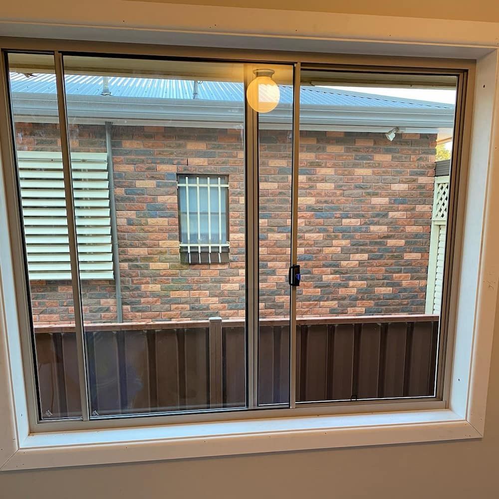 A Window With a View of a Brick Wall, Brown Fence — Ingrams Installations in Cootamundra, NSW