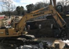 A yellow excavator is working on a construction site next to a river.