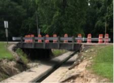 A bridge over a stream with orange cones on it