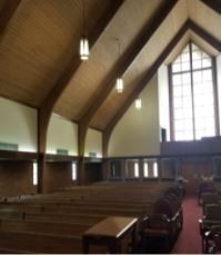 A church with rows of wooden benches and a large window