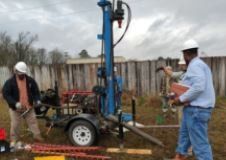 A group of men are working on a drilling rig in a field.